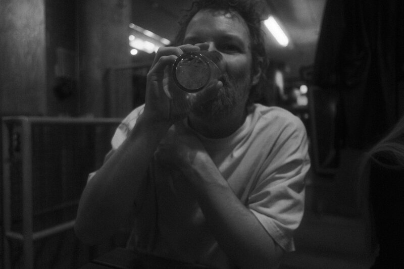 Black-and-white photo of a man holding an empty glass up to his face and peering through it